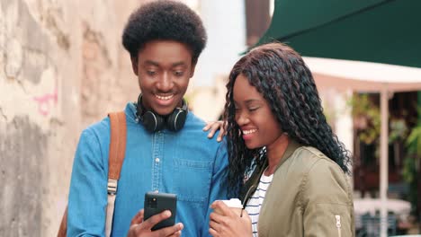 Afroamerikanischer-Mann-Und-Frau,-Die-Etwas-In-Einem-Smartphone-Auf-Der-Straße-Beobachten