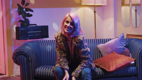 Caucasian-happy-young-woman-with-blonde-hair-taking-pictures-to-the-camera-while-sitting-on-sofa-in-a-retro-room-at-home