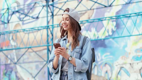 Caucasian-girl-wearing-cap-texting-on-the-smartphone-in-the-street