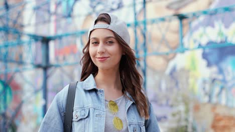 Caucasian-woman-in-hipster-style-wearing-cap-and-looking-at-the-camera-in-the-street