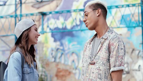 Caucasian-smiling-woman-in-hipster-style-wearing-cap-and-talking-with-her-boyfriend-in-the-street