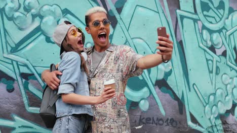 Hipster-funny-couple-in-stylish-clothes-making-a-selfie-with-smartphone-in-the-street
