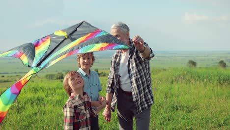Close-up-view-of-a-caucasian-senior-man-with-his-grandchildren-in-the-park-while-they-are-flying-a-kite-on-a-sunny-day