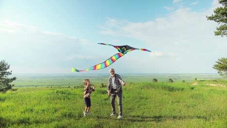 Caucasian-senior-man-with-his-grandson-in-the-park-while-they-are-flying-a-kite-on-a-sunny-day