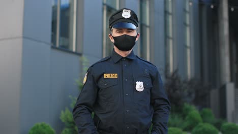 Kaukasischer-Hochrangiger-Polizist-Mit-Gesichtsmaske-Und-Uniform,-Der-Auf-Der-Straße-In-Die-Kamera-Blickt