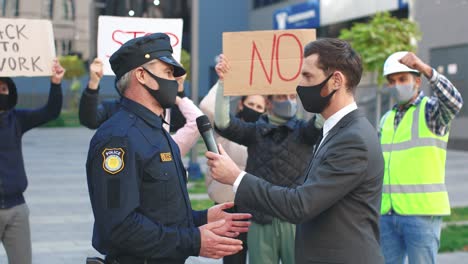 Kaukasischer-Journalist-Oder-Korrespondent-Mit-Schutzmaske-In-Einem-Interview-Mit-Einem-Polizisten-Aus-Protest-Gegen-Covid-19
