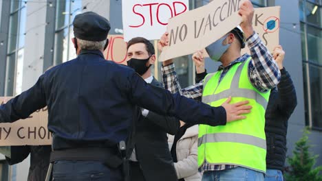 Polizist-Stoppt-Eine-Gruppe-Von-Menschen-Bei-Einer-Demonstration-Gegen-Covid-19-Auf-Der-Straße