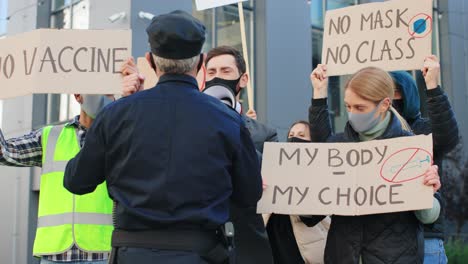 Polizist-Stoppt-Eine-Gruppe-Von-Menschen-Bei-Einer-Demonstration-Gegen-Covid-19-Auf-Der-Straße