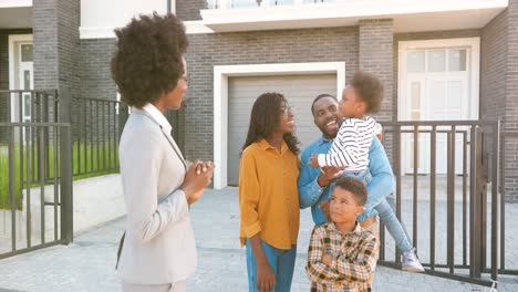 Female-real-estate-handing-keys-to-African-American-happy-family-with-kids