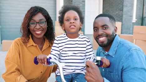 Porträt-Einer-Jungen-Afroamerikanischen-Glücklichen-Familie-Mit-Einem-Kleinen-Süßen-Mädchen-Auf-Dem-Fahrrad,-Das-Draußen-In-Die-Kamera-Lächelt