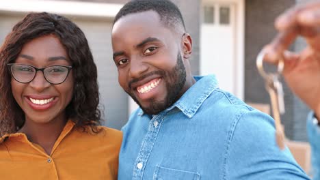 Close-up-happy-young-African-American-man-and-woman-smiling-to-camera-and-showing-key-of-new-home