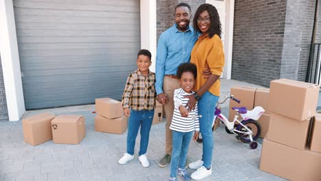 Portrait-of-happy-African-American-family-with-small-children-at-new-house-in-suburb-smiling