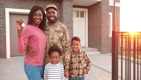 Portrait-of-African-American-family-of-army-officer-with-little-kids-moving-in-new-house-and-showing-keys