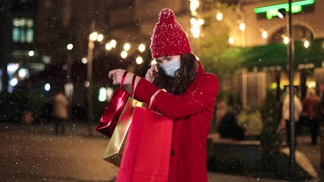 Porträt-Einer-Glücklichen,-Schönen-Jungen-Frau,-Die-Auf-Dem-Smartphone-Spricht-Und-Einkaufstüten-Auf-Der-Straße-Hält,-Während-Es-In-Weihnachten-Schneit