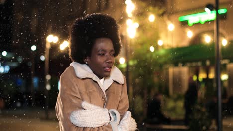 Nahaufnahme-Einer-Afroamerikanischen-Frau,-Die-Erkältet-Ist-Und-Versucht,-Sich-Auf-Der-Straße-Aufzuwärmen,-Während-Es-Zu-Weihnachten-Schneit