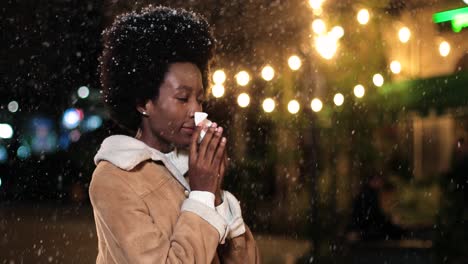 Close-up-view-of-sick-african-american-woman-in-red-coat-blowing-her-nose-on-the-street-while-it¬¥s-snowing-in-Christmas