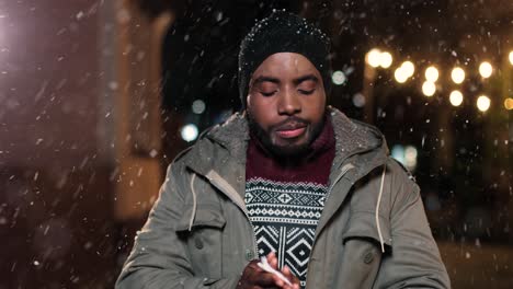 Close-up-view-of-sick-african-american-man-in-grey-coat-blowing-her-nose-on-the-street-while-it¬¥s-snowing-in-Christmas