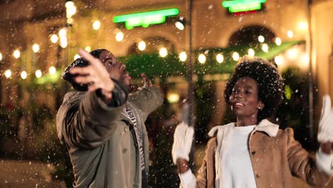 Nahaufnahme-Eines-Fröhlichen-Afroamerikanischen-Paares,-Das-Zu-Weihnachten-Mit-Dem-Schnee-Auf-Der-Straße-Spielt