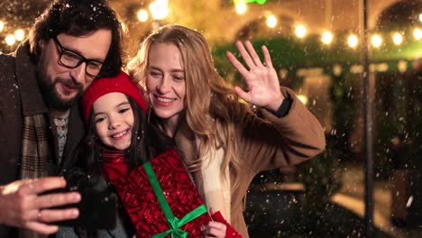 Nahaufnahme-Einer-Kaukasischen-Glücklichen-Familie,-Die-Geschenke-Hält-Und-Ein-Selfie-Macht,-Während-Es-Zu-Weihnachten-Schneit