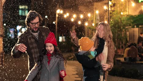Close-up-view-of-Caucasian-happy-family-playing-with-the-snow-on-the-street-in-Christmas