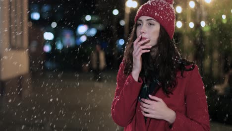 Close-up-view-of-sick-Caucasian-woman-in-red-coat-outdoor-sneezing-on-the-street-while-it¬¥s-snowing-in-Christmas