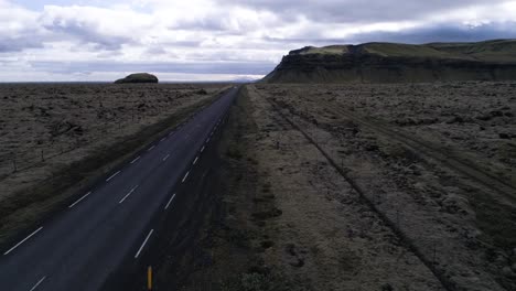 Ring-road-drone-shot-in-iceland-with-car-and-volcanic-stone-covered-in-moss