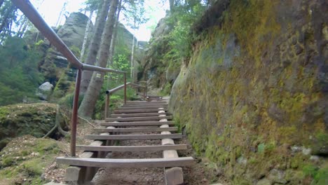 Walking-up-wooden-stairs-in-between-rocks-in-national-park-Adršpach