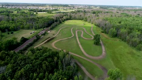 Aerial-flyover-of-motorcycle-dirt-track-hidden-in-woods-along-large-lake