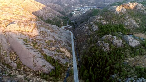 Aerial-footage-of-a-straight-road-that-goes-over-to-a-winding-road-leading-down-to-a-fjord