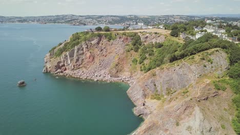 Flying-over-ocean-cliffs-in-Torquay,-England