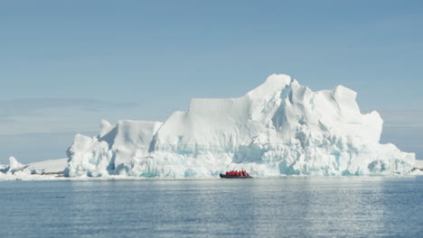 Ein-Zodiac-Manövriert-Unter-Einem-Riesigen-Eisberg-In-Der-Antarktis
