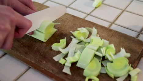 Cutting-a-leek-on-wooden-board-in-kitchen,-vegetable,-356%-speed