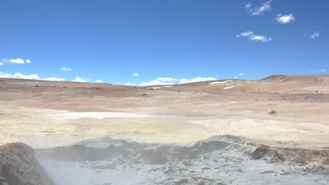 A-wide-shot-of-the-desert-on-the-border-of-Bolivia-and-Chile,-a-muddy-volcanic-pool-in-the-foreground