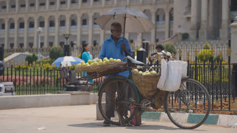 Vendedor-De-Frutas-Con-Bicicleta-Fuera-Del-Edificio-De-La-Asamblea-Legislativa-Vidhana-Soudha-En-Bangalore,-India