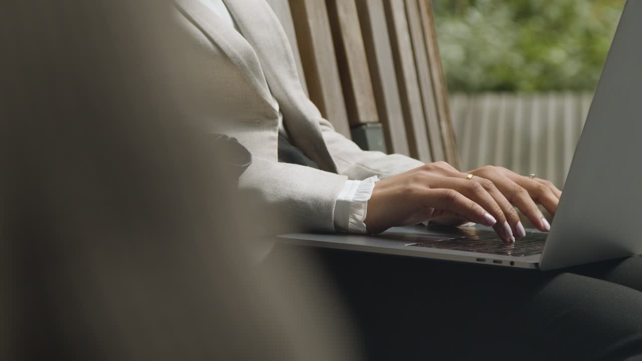 Closeup del braccio della mano della donna che scrive lavorando con una penna  su un documento vicino al suo PC portatile del calcolatore nel suo ufficio  domestico sul suo allievo del posto