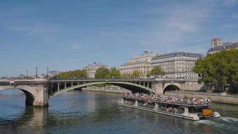 Touristenboot-Fährt-Unter-Der-Brücke-Pont-Notre-Dame-über-Die-Seine-In-Paris,-Frankreich,-Mit-Touristen-Und-Verkehr-1