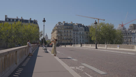 Female-Tourists-Standing-On-Bridge-Taking-Pictures-Of-Each-Other-In-Quais-De-Seine-District-Of-Paris-France