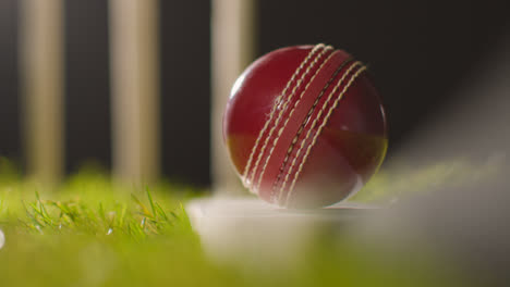Cricket-Stillleben-Mit-Nahaufnahme-Eines-Balls-Auf-Einem-Schläger,-Der-Im-Gras-Vor-Stümpfen-Liegt-3