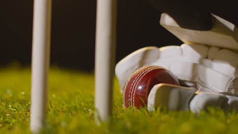 Cricket-Stillleben-Mit-Nahaufnahme-Eines-Schlägerballs-Und-Handschuhen,-Die-Im-Gras-Hinter-Stümpfen-Liegen-3