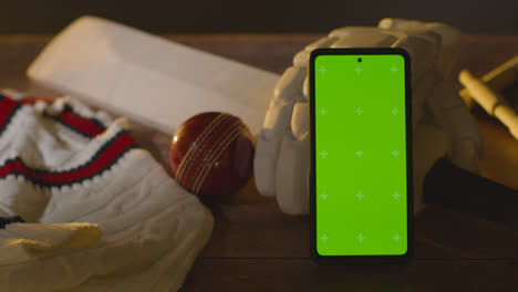 Greenscreen-Handy-Umgeben-Von-Cricketschlägerball-Und-Kleidung-Auf-Holzoberfläche-1