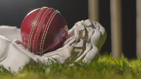 Cricket-Stillleben-Mit-Nahaufnahme-Eines-Balls,-Der-Im-Handschuh-Auf-Gras-Vor-Stümpfen-Liegt-1