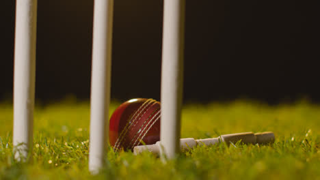 Cricket-Stillleben-Mit-Nahaufnahme-Von-Kautionen-Und-Ball-Im-Gras-Hinter-Stümpfen