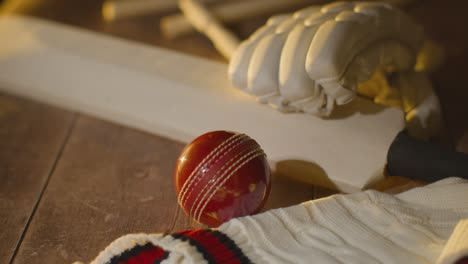 Cricket-Still-Life-With-Close-Up-Of-Bat-Ball-Gloves-Stumps-Jumper-And-Bails-Lying-On-Wooden-Surface-In-Locker-Room-4
