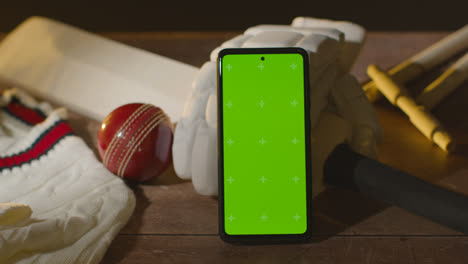 Greenscreen-Handy-Umgeben-Von-Cricketschlägerball-Und-Kleidung-Auf-Holzoberfläche-2