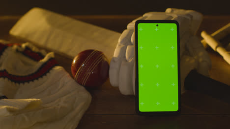 Greenscreen-Handy-Umgeben-Von-Cricketschlägerball-Und-Kleidung-Auf-Holzoberfläche-3