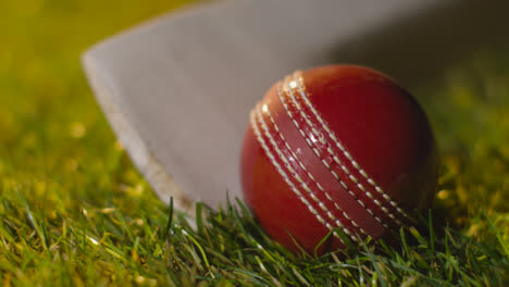 Cricket-Stillleben-Mit-Nahaufnahme-Von-Ball-Und-Schläger,-Die-Im-Gras-Liegen