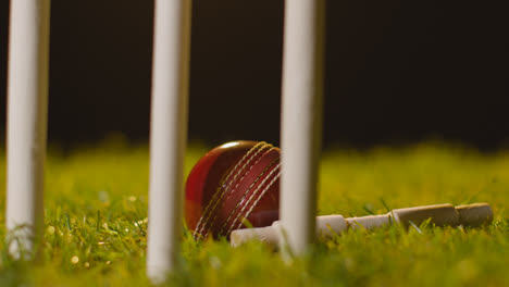 Cricket-Stillleben-Mit-Nahaufnahme-Von-Bügeln-Und-Ball-Im-Gras-Hinter-Stümpfen-1