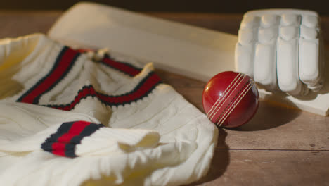 Cricket-Still-Life-With-Close-Up-Of-Bat-Ball-Gloves-Stumps-Jumper-And-Bails-Lying-On-Wooden-Surface-In-Locker-Room-1