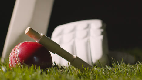 Cricket-Stillleben-Mit-Nahaufnahme-Von-Im-Gras-Liegenden-Schlägerballbügeln-Und-Handschuhen-1