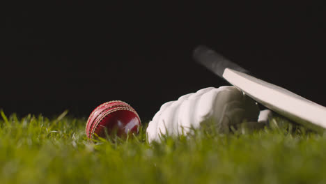 Cricket-Stillleben-Mit-Nahaufnahme-Eines-Schlägerballs-Und-Handschuhen,-Die-Im-Gras-Liegen-Und-In-Den-Fokus-Gerückt-Sind